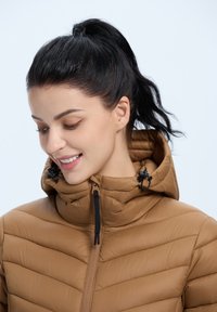 Bruine opblaasbare jas met een hoge kraag, horizontale quilt, zwarte rits en verstelbare trekkoorden bij de capuchon. Gladde materiaaldot.