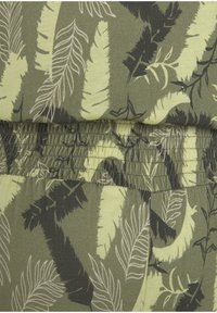 Olivegrüne Shorts mit elastischem Bund aus Stoff, der ein Blattmuster in Schwarz und blassem Gelb zeigt, mit einem gerafften Bunddesign.