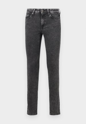 Jeans in denim nero con vestibilità slim, design a cinque tasche e chiusura con bottone metallico. Presentano una texture usurata e una leggera scoloritura.