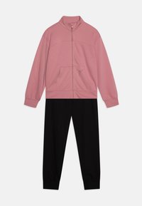 Veste zippée rose avec un col montant et une poche avant, associée à un pantalon de jogging noir. Tissu doux, design décontracté, poignets élastiques.