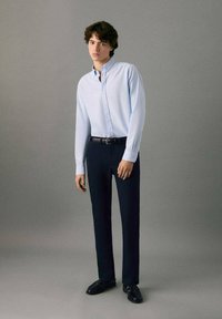 Svetlomodrá košeľa s dlhými rukávmi, tmavomodré nohavice; čierny opasok; čierne topánky; hladká textúra; moderný strih. Jednoduchý, klasický dizajn.