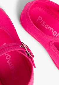 Helle pinke Canvas-Schuhe mit runder Zehenpartie, ausgestattet mit einer metallischen Schnalle und strukturiertem Obermaterial. Das Innere hat eine Markenkennzeichnung in einem helleren Farbton.