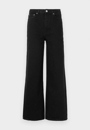 Melnas platas kājas džinsi no džinsa auduma; tiem ir augsts viduklis, priekšējās kabatas un pogas aizdare. Nav redzamu rakstu vai rotājumu.