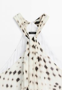White sleeveless dress with layered straps and black spotted pattern, showing back neck area and brand label Massimo Dutti.