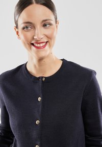 Granatowy kardigan wykonany z miękkiego dzianiny, z okrągłym dekoltem i zapięciem na złote guziki z przodu. Gładka tekstura z dopasowanymi rękawami.