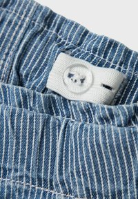 Striped blue fabric waistband with white stitching and a circular clear button. The stripes are narrow and evenly spaced.