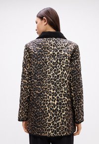 Kabát s leopardím potiskem a prošívanou strukturou, černým límcem, s mírně oversize střihem a viditelným šitím na látce.