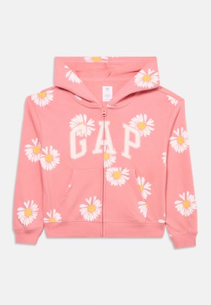 Rožnata jopa s kapuco z belo vzorčastimi marjeticami z rumenimi sredicami, z velikimi belimi črkami "GAP" čez prsni del in sprednjim žepom.