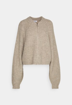 Beige gestrickte verkürzte Strickjacke mit gerippter Textur, Reißverschluss vorne, runden Halsausschnitt und voluminösen Ärmeln. Schlichtes Design ohne zusätzliche Muster.