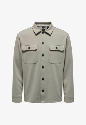 Camisa abotonada gris claro con cuello, dos bolsillos en el pecho con solapas y botones negros. Hecha de una tela texturizada con mangas largas.