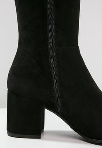 Czarne zamszowe botki za kostkę z grubym obcasem, z zamkiem bocznym i gładką fakturą, zaprojektowane z myślą o łatwym zakładaniu.