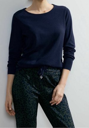 Navy knitted long-sleeve sweater with a round neck, paired with green patterned joggers featuring a drawstring waist and lightweight fabric.