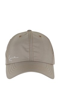 Beige caps laget av stoff med en glatt tekstur. Har søm langs skyggen og et signaturdetalj på venstre framside.