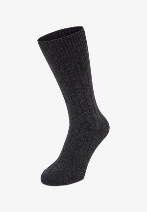 Dunkelgrauer, gerippter Socken mit langer, zulaufender Form. Hergestellt aus strukturiertem Stoff, mit vertikalen Linien entlang des Körpers für zusätzliche Details.