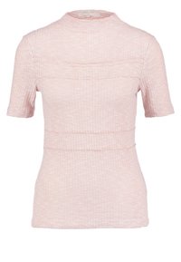 Růžový top s krátkým rukávem vyrobený z texturované tkaniny, s vysokým límcem a vodorovným švem přes hruď a pas.