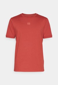 Czerwona bawełniana koszulka z okrągłym dekoltem i krótkimi rękawami. Posiada małe kwadratowe logo na przodzie. Gładka tekstura i klasyczny krój.