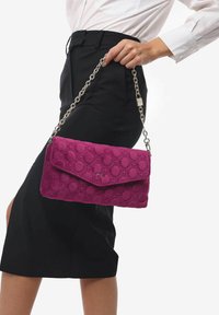 Borsa a tracolla di colore viola, trapuntata, con una tracolla a catena e chiusura a calamita, caratterizzata da un motivo testurizzato e una silhouette elegante.
