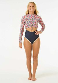 Maillot de bain à manches longues avec un motif floral multicolore, section centrale découpée et bas taille haute bleu marine avec des accents crème.