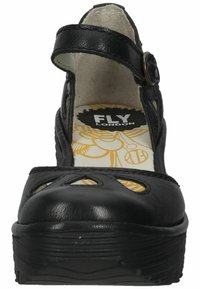 Black leather platform shoes with cutout design, ankle strap, and textured sole. Features yellow patterned insole with "FLY London" branding.
