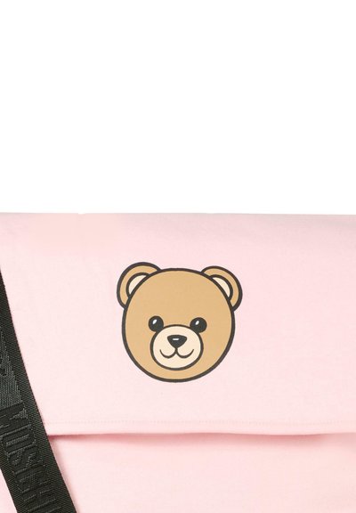 Borsa di stoffa rosa con una grafica di faccia d'orso sulla patta. Presenta una tracolla nera per il trasporto. Texture liscia con un design semplice.