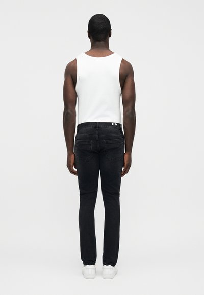 Λευκό αμάνικο τοπ και μαύρο τζιν που φορώντας ένα άτομο από πίσω, με εφαρμοστή σχεδίαση και μινιμαλιστικό στυλ. Ορατά λευκά αθλητικά παπούτσια.