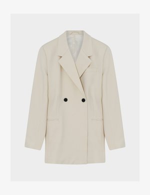 Kremasti dvostruko kopčani sako s crnim gumbima, reverima s urezima, dva prednja džepa i jednim džepom na prsima, prikazan položen ravno na bijeloj pozadini.