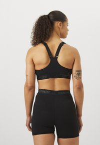 Conjunto de sutiã desportivo e calções pretos com um design de costas nadador, logótipo Venum e tecido suave e elástico. Adequado para vestuário activo.