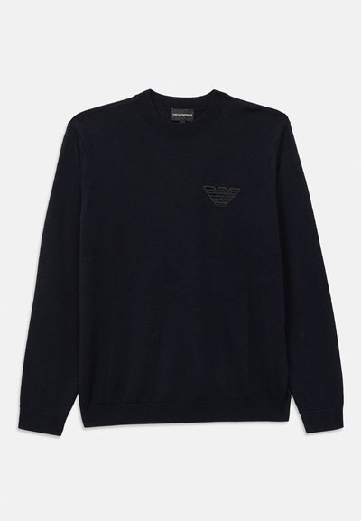 Suéter negro de cuello redondo hecho de una tela suave, con mangas largas y un sutil logo bordado en el pecho. Puños y dobladillo de canalé.