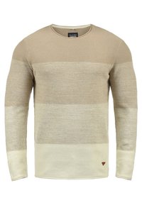 Pull beige à manches longues avec des rayures horizontales de différentes teintes, doté d'un col rond et d'un petit logo triangulaire en bas.