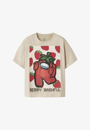 T-shirt beige à manches courtes avec un personnage rouge de dessin animé portant un haut fraise, entouré de fraises, avec le texte « BERRY BASHFUL » en dessous.
