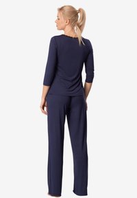 Granatowy zestaw odzieży domowej z luźnym krojem, rękawami o długości trzech czwartych i szerokimi spodniami, wykonany z miękkiego, lekkiego materiału.