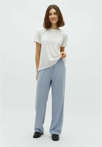 White short-sleeve t-shirt paired with light blue wide-leg trousers, both made from soft fabric. Black shoes complete the outfit.
