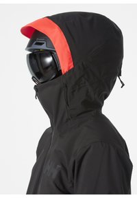 Schwarze wasserdichte Jacke mit roten Akzenten an der Kapuze, ausgestattet mit einem Reißverschluss vorne und einem Logo auf der Brust, entworfen für Outdoor-Aktivitäten.