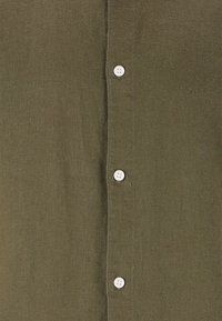 Oliivinvihreä nappikauluspaita, joka on valmistettu teksturoidusta kankaasta ja jossa on valkoiset napit edessä sekä siisti ja yksinkertainen muotoilu.