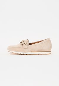 Beige semsket slip-on sko med en dekorativ sløyfe, kile såle, og hvit aksentstripe langs bunnen, med en teksturert finish.