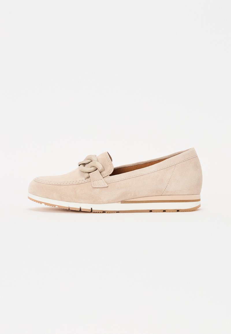 Beige semsket slip-on sko med en dekorativ sløyfe, kile såle, og hvit aksentstripe langs bunnen, med en teksturert finish.