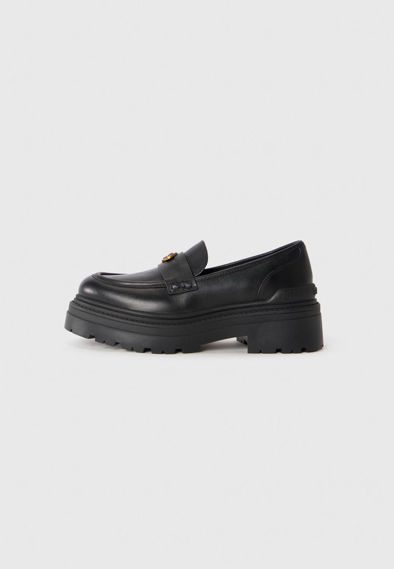 Black leather loafer with chunky textured sole and a gold buckle detail on the top, set against a plain light background.