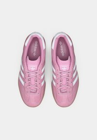 Rosa ruskinds sneakers med hvide striber, rund tå og snørebåndsdesign. Har en tekstureret tunge og gummisål for et godt greb.