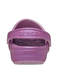 Glanzende roze Crocs van achteren, met een band en een textuur van binnenin. De merknaam "CROCS" is zichtbaar op de hiel.