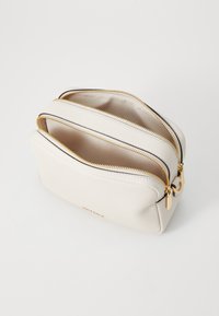 Cream-colored leather cosmetic bag with two zippered compartments and gold hardware accents. Textured surface with a smooth interior.