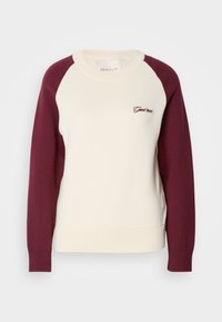 Long-sleeve crewneck sweater with cream body, maroon sleeves, ribbed cuffs and hem, and small embroidered "Gant 1949" on chest.