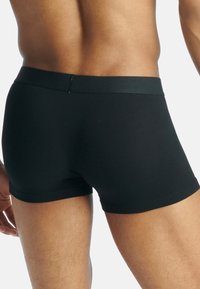 Sorte boxershorts laget av mykt materiale med et teksturert, elastisk liv. Tett passform uten synlige mønstre eller aksenter.