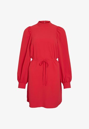 Punainen pitkähihainen mekko, jossa on puffettiset olkapäät, kireä vyötärö, joka on sidottu yhteensopivalla vyöllä, sekä korkea kaula ja takakappaleen nappikiinnitys.