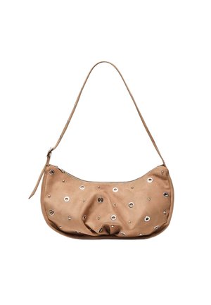 Beige leren schoudertas met zilveren oogjes en studs, ritssluiting en verstelbare band op een witte achtergrond.