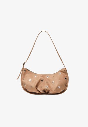 Beige leren schoudertas met zilveren oogjes en studs, ritssluiting en verstelbare band op een witte achtergrond.