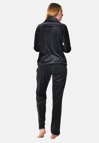 Black velour loungewear set featuring a high-collar jacket and matching pants, showcasing a soft texture and relaxed fit.