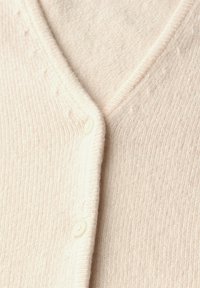 Cardigan rosa chiaro realizzato in morbido tessuto a maglia a coste. Presenta un collo a V e due bottoni bianchi sul davanti.