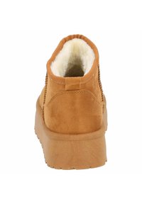 Světlé hnědé semišové platformové boty s tlustou podrážkou a bílou nadýchanou podšívkou, pohled zezadu.