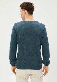 Dunkelblauer Pullover mit rundem Halsausschnitt, langen Ärmeln, gerippten Bündchen und glatter Stricktextur.