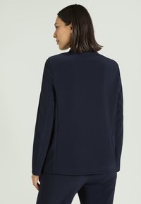 Marineblazer mit strukturiertem Design, glattem Stoff und ohne sichtbare Verschlüsse, ausgestattet mit geradem Schnitt und langen Ärmeln.